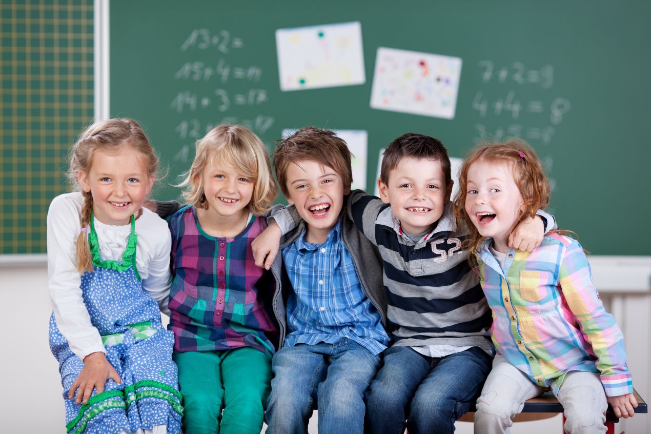 Fünf lachende Kinder vor Tafel in Schulklasse – Motiv für positive Bildungserfahrungen und kosten privatschule berlin im Fokus