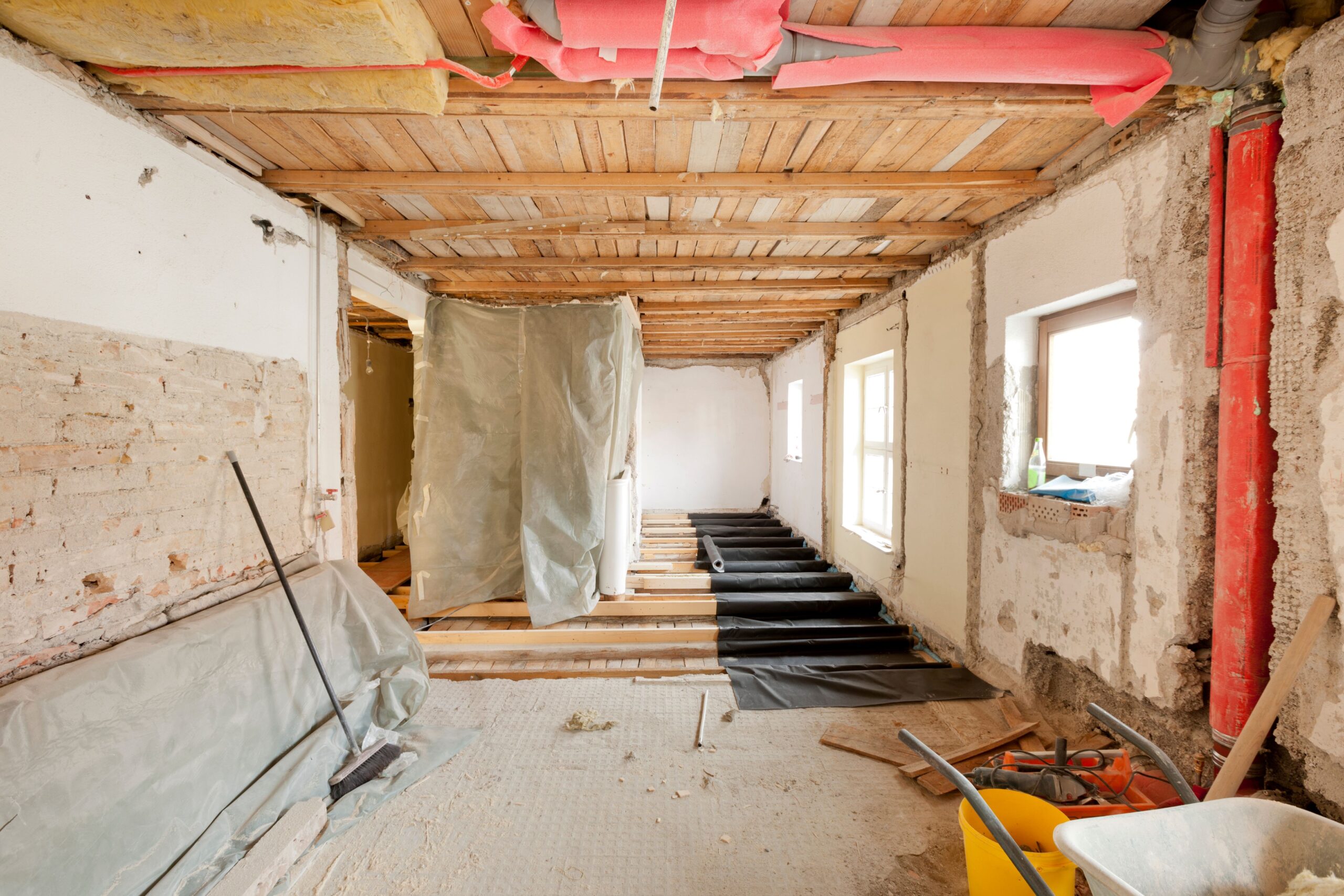 Altbau im Sanierungszustand mit freigelegten Böden, offenen Leitungen und Dämmmaterial